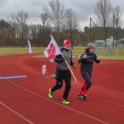zawodnicy podczas biegu z flagą WOŚP